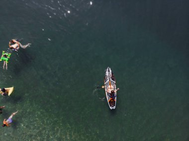 Stand Up Paddle tahtasında çekici bir kadın yemek masasında kürek çeken ve şeffaf suyun tadını çıkaran bir kadın. Tropik seyahat, seyahat tutkusu ve su aktivitesi konsepti. Gün batımı ve rahatlama