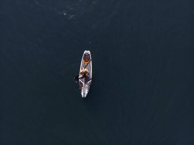 Stand Up Paddle tahtasında çekici bir kadın yemek masasında kürek çeken ve şeffaf suyun tadını çıkaran bir kadın. Tropik seyahat, seyahat tutkusu ve su aktivitesi konsepti. Gün batımı ve rahatlama