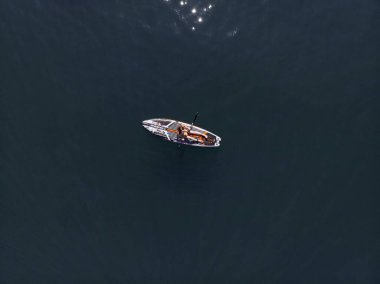 Stand Up Paddle tahtasında çekici bir kadın yemek masasında kürek çeken ve şeffaf suyun tadını çıkaran bir kadın. Tropik seyahat, seyahat tutkusu ve su aktivitesi konsepti. Gün batımı ve rahatlama