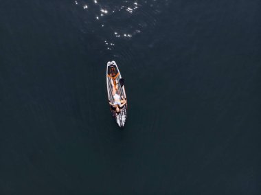 Stand Up Paddle tahtasında çekici bir kadın yemek masasında kürek çeken ve şeffaf suyun tadını çıkaran bir kadın. Tropik seyahat, seyahat tutkusu ve su aktivitesi konsepti. Gün batımı ve rahatlama