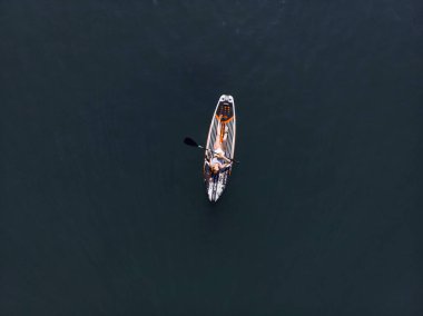 Stand Up Paddle tahtasında çekici bir kadın yemek masasında kürek çeken ve şeffaf suyun tadını çıkaran bir kadın. Tropik seyahat, seyahat tutkusu ve su aktivitesi konsepti. Gün batımı ve rahatlama