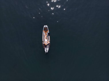 Stand Up Paddle tahtasında çekici bir kadın yemek masasında kürek çeken ve şeffaf suyun tadını çıkaran bir kadın. Tropik seyahat, seyahat tutkusu ve su aktivitesi konsepti. Gün batımı ve rahatlama