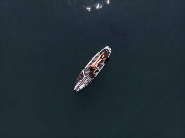 Stand Up Paddle tahtasında çekici bir kadın yemek masasında kürek çeken ve şeffaf suyun tadını çıkaran bir kadın. Tropik seyahat, seyahat tutkusu ve su aktivitesi konsepti. Gün batımı ve rahatlama