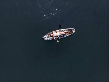 Stand Up Paddle tahtasında çekici bir kadın yemek masasında kürek çeken ve şeffaf suyun tadını çıkaran bir kadın. Tropik seyahat, seyahat tutkusu ve su aktivitesi konsepti. Gün batımı ve rahatlama