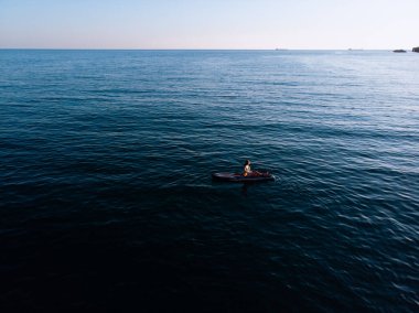 Stand Up Paddle tahtasında çekici bir kadın yemek masasında kürek çeken ve şeffaf suyun tadını çıkaran bir kadın. Tropik seyahat, seyahat tutkusu ve su aktivitesi konsepti. Gün batımı ve rahatlama