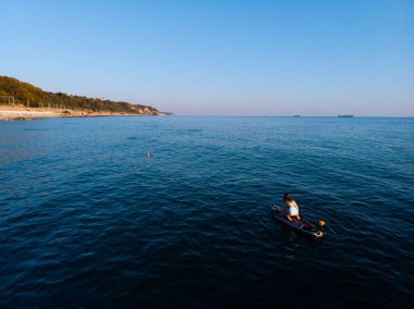 Stand Up Paddle tahtasında çekici bir kadın yemek masasında kürek çeken ve şeffaf suyun tadını çıkaran bir kadın. Tropik seyahat, seyahat tutkusu ve su aktivitesi konsepti. Gün batımı ve rahatlama