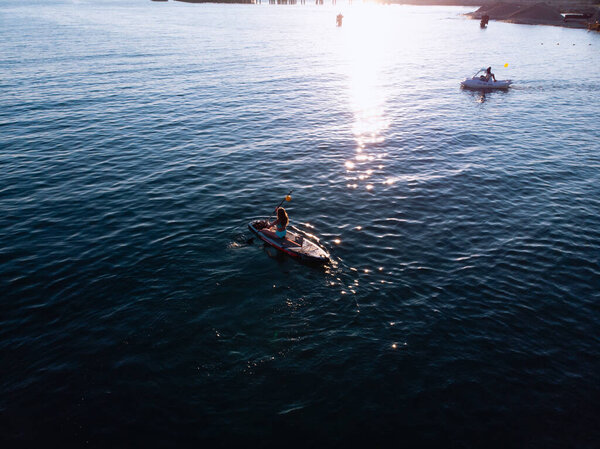 Attractive Woman on Stand Up Paddle Board, Woman paddling on sup board and enjoying turquoise transparent water. Tropical travel, wanderlust and water activity concept. Sunset and relax