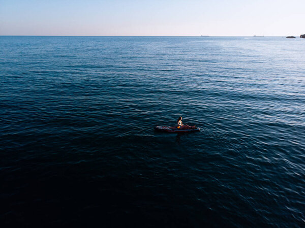 Attractive Woman on Stand Up Paddle Board, Woman paddling on sup board and enjoying turquoise transparent water. Tropical travel, wanderlust and water activity concept. Sunset and relax