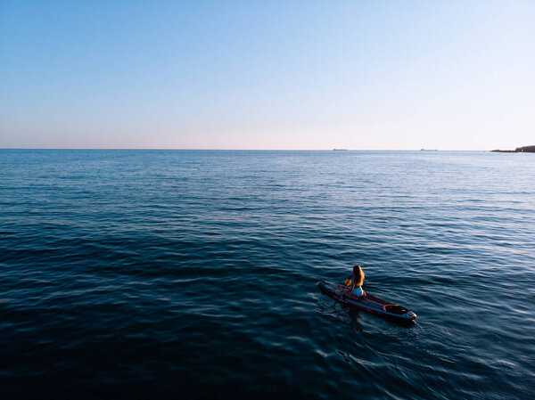 Attractive Woman on Stand Up Paddle Board, Woman paddling on sup board and enjoying turquoise transparent water. Tropical travel, wanderlust and water activity concept. Sunset and relax