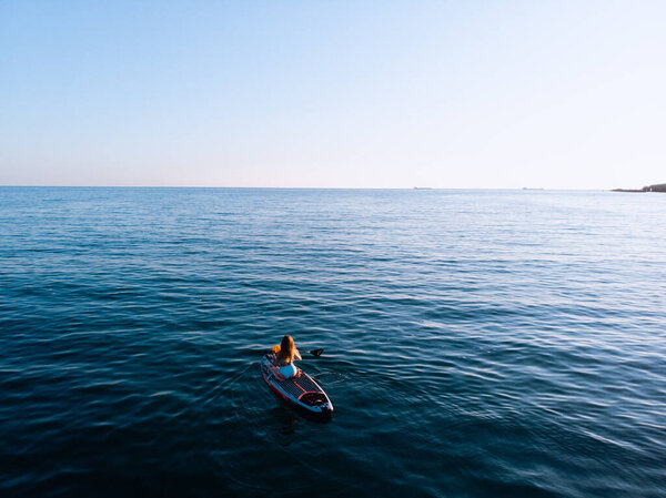 Attractive Woman on Stand Up Paddle Board, Woman paddling on sup board and enjoying turquoise transparent water. Tropical travel, wanderlust and water activity concept. Sunset and relax
