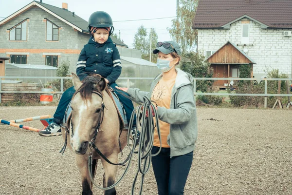 A child with special needs is riding with a close supervision teacher. This is a treatment called Hippotherapy, Life in the education age of disabled children, Happy disability kid concept. quarantine
