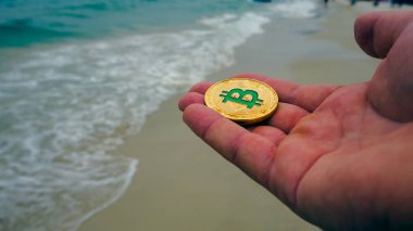 El tutma altın bitcoin, plaj