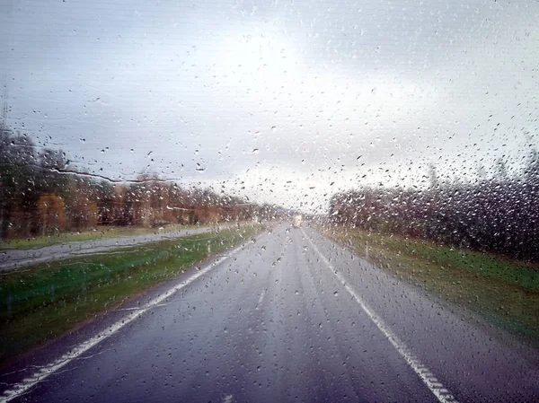 Капля дождя на стекле автомобиля с размытым фоном — стоковое фото