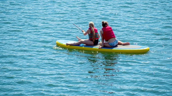 Sittiing en peddelen op blauw water — Stockfoto