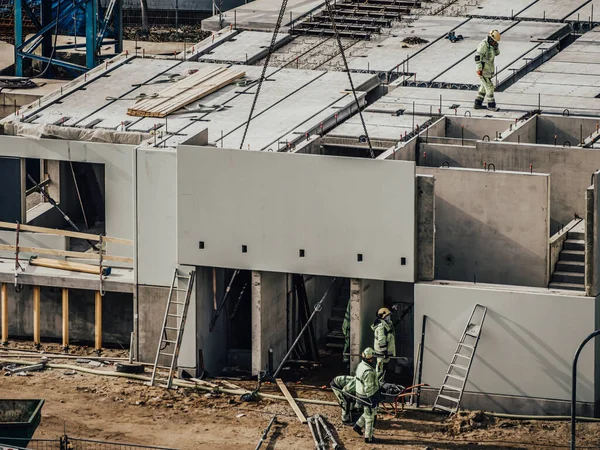 Vinçli inşaatçılar çok katlı ev inşa ediyorlar. Kış ya da sonbahar arka planı. Apartman dairesinde vinçli işçiler. Mavi gökyüzünün altında. İş konsepti. Boşluğu kopyala. 