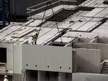Vinçli inşaatçılar çok katlı ev inşa ediyorlar. Kış ya da sonbahar arka planı. Apartman dairesinde vinçli işçiler. Mavi gökyüzünün altında. İş konsepti. Boşluğu kopyala. 