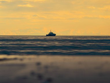 Küçük bir balıkçı teknesi şafak vakti sisli okyanusa açılacak. Günbatımının arka planında bir tekne. Baltık Denizi kapanıyor, fırtınalı, dramatik kara bulutlar. Tatil, yaz konsepti