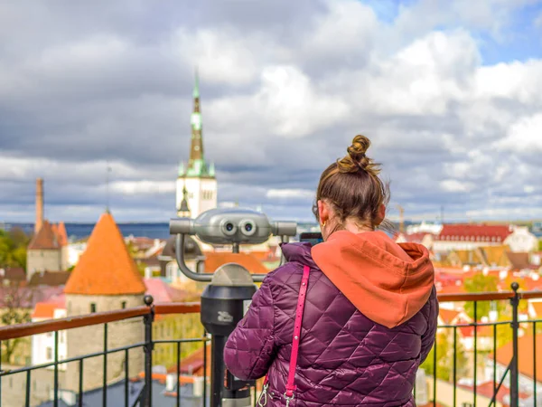 Kadın şehre doğru bakıyor ve akıllı telefonuyla eski kasabanın fotoğrafını çekiyor. Estonya 'da Turist