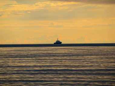 Küçük bir balıkçı teknesi şafak vakti sisli okyanusa açılacak. Günbatımının arka planında bir tekne. Baltık Denizi kapanıyor, fırtınalı, dramatik kara bulutlar. Tatil, yaz konsepti