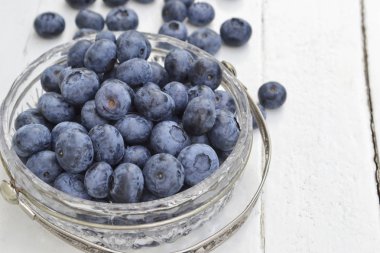 Beyaz zemin üzerinde bir kristal kase taze yaban mersini. Kopya alanı