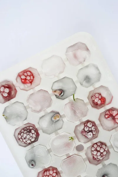 Ice cubes with berries. Ice tray with berries on white background. Top view
