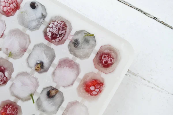 Ice cubes with berries. Ice tray with berries on white background. Top view