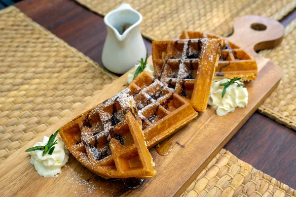 Waffle çikolata şeker ve şurubu bir ahşap plaka üzerinde buzlanma ile