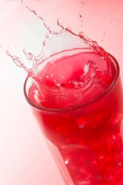 Närbild Ett Plask Ett Glas Jordgubbs Saft Mot Röd Bakgrund — Stockfoto