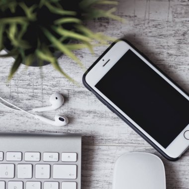 Şık çalışma alanı. Akıllı telefon ve kulaklık Beyaz ahşap masa üzerinde klavye ile. 