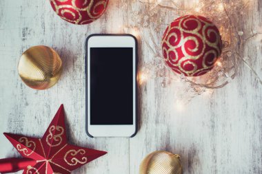 Beyaz ahşap zemin Noel oyuncaklar ve ışıklar ile Smartphone