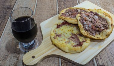 Lezzetli Arapça Esfiha, dolgu peynir ve domates ve soğan ile et. Ahşap bir gemide hizmet.