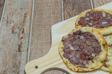 Lezzetli Arapça Esfiha, dolgu peynir ve domates ve soğan ile et. Ahşap bir gemide hizmet.