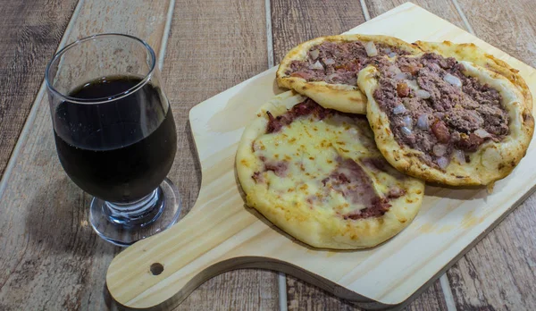 Lezzetli Arapça Esfiha, dolgu peynir ve domates ve soğan ile et. Ahşap bir gemide hizmet.