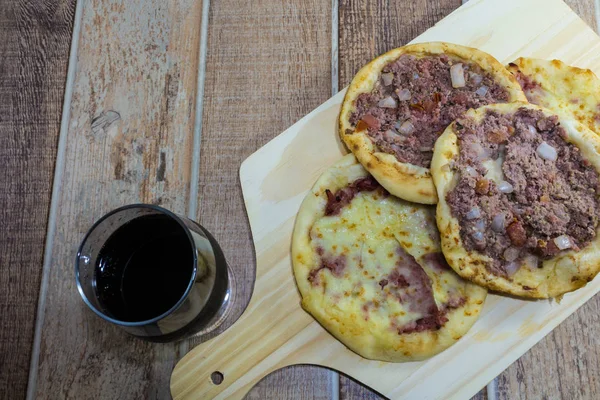 Lezzetli Arapça Esfiha, dolgu peynir ve domates ve soğan ile et. Ahşap bir gemide hizmet.