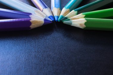 İzole kopya alanı için metin ile siyah arka plan üzerinde renkli kalemler.