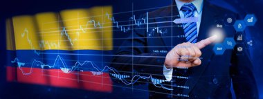 İş adamı KPI finansal grafikleri, sanal arayüzdeki stok ve pazarlama paneli ile veri analiz süreci sistemine dokunuyor. Arka planda Kolombiya bayrağı.