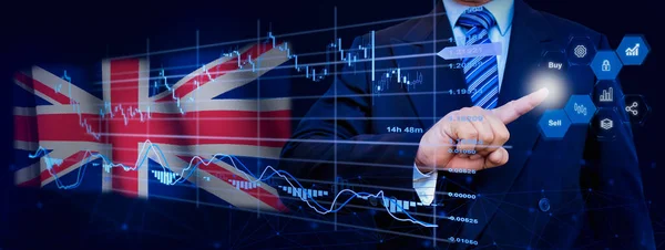 İş adamı KPI finansal grafikleri, sanal arayüzdeki stok ve pazarlama paneli ile veri analiz süreci sistemine dokunuyor. Arka planda Birleşik Krallık bayrağı.