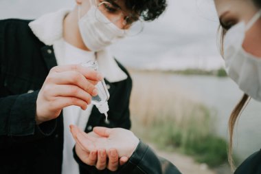 Adam kız arkadaşının ellerini dezenfekte ediyor.