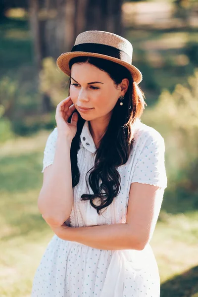 Aantrekkelijk meisje in een hoed en een witte jurk Stockfoto