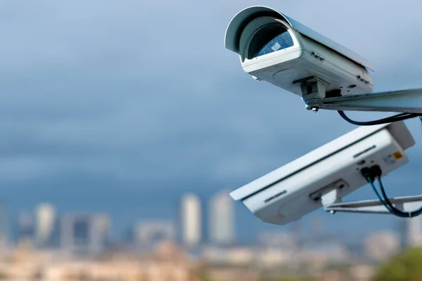 Focus on security CCTV camera monitoring system with panoramic view of a city on blurry background