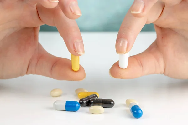 白い机の上の下のカラフルな錠剤で薬を選択する若い女性をクローズ アップ — ストック写真