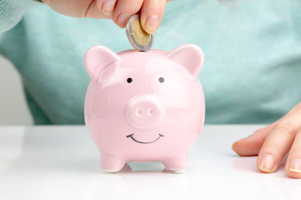 Woman Putting Coin In Piggy Bank, Indoors