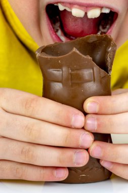 Mutlu genç çocuk çikolata Paskalya tavşanı kulağını ısırıp