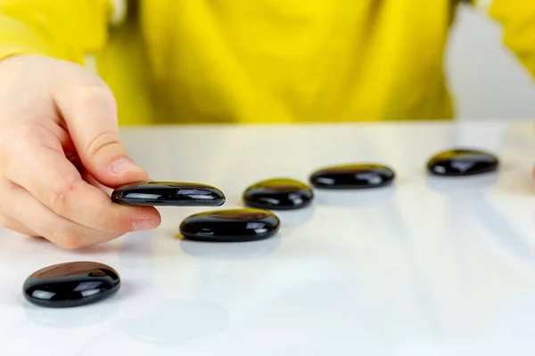 Enfant Jouant Avec Des Pierres Noires Sur Une Table Blanche — Photo