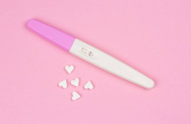 pembe bir arka plan üzerinde küçük kalpler ile gebelik testi pozitif sonuç
