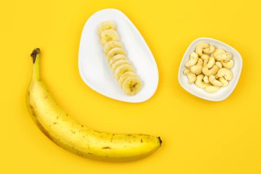 Çiğ Vegan kahvaltı: muz, fındık ve sarı zemin üzerine çilek