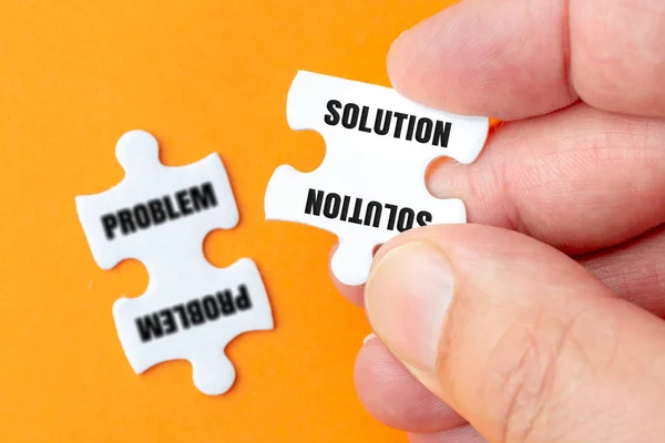 Solution Puzzle in the hands with a problem puzzle in the background. — Stock Photo, Image