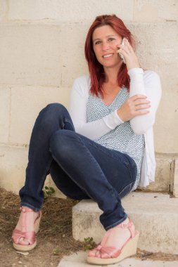 Sevimli gülümseyen kızıl saçlı kadın cep telefonu ile bir arama yapma