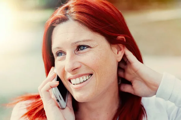 Gülümseyen güzel genç kadın cep telefonu ile yakın, yaz yeşil park arka plan karşı. — Stok fotoğraf