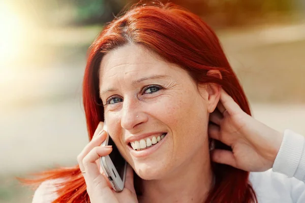 Smiling beautiful young woman close up with mobile phone, against background of summer green park. — Stock Photo, Image
